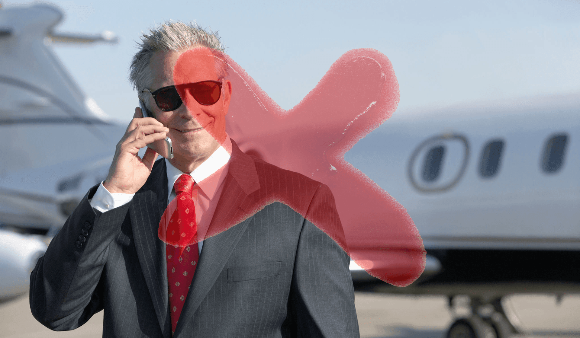 Person in a suit with a red tie talking on the phone, standing near a private jet.